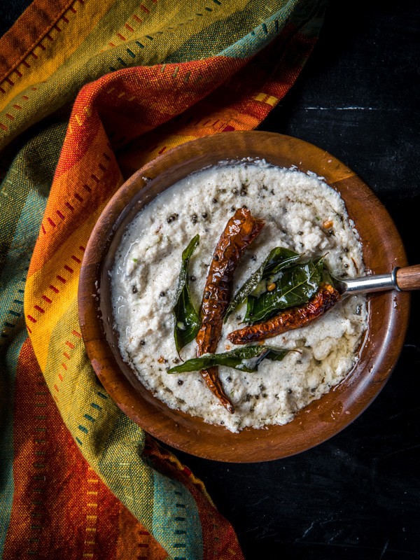 Coconut chutney served in a brown bowl tempered with red chilies and curry leaves.
