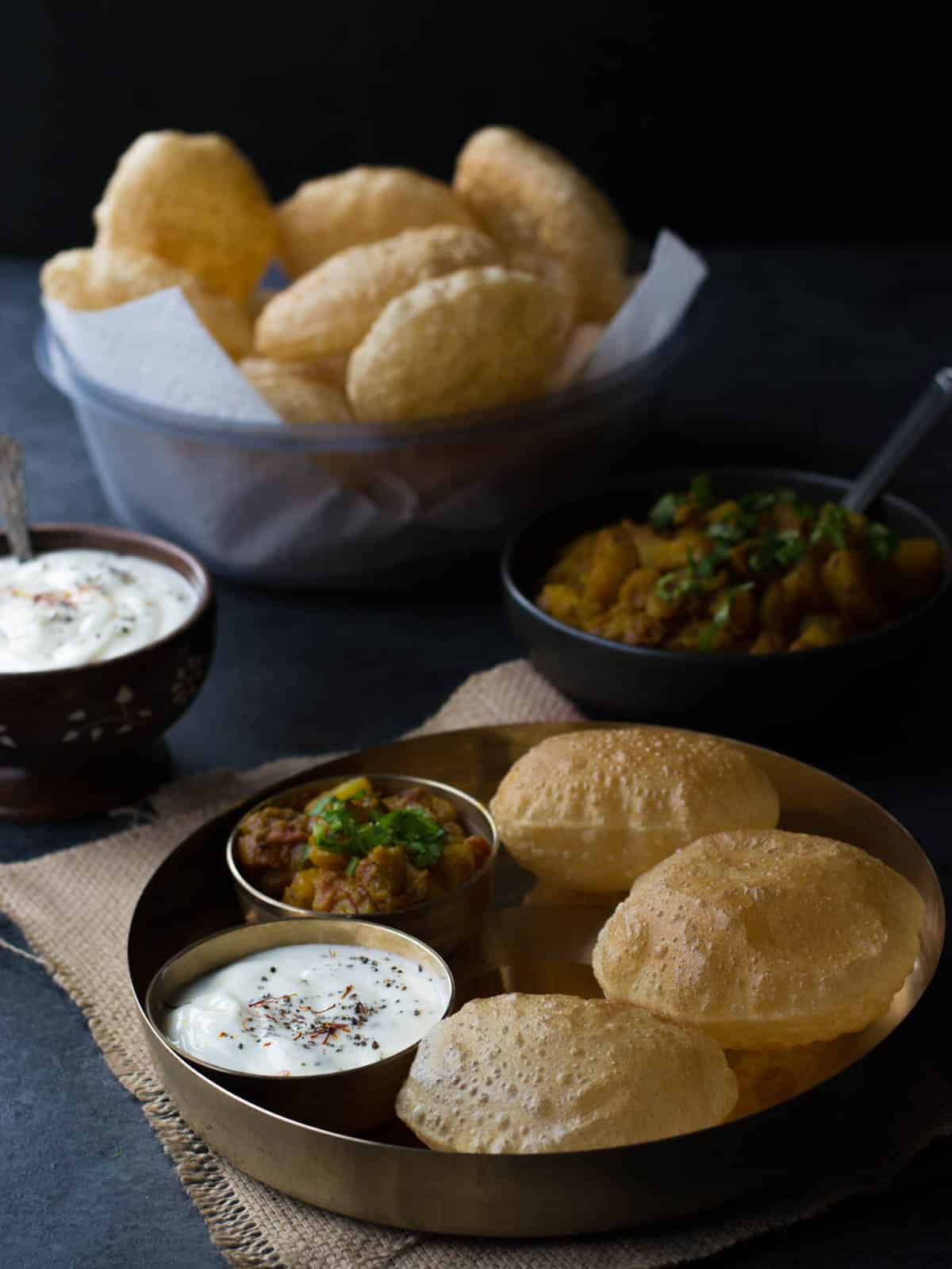 Poori, Shrikhand and Potato vegetable dish served in a golden plate. 