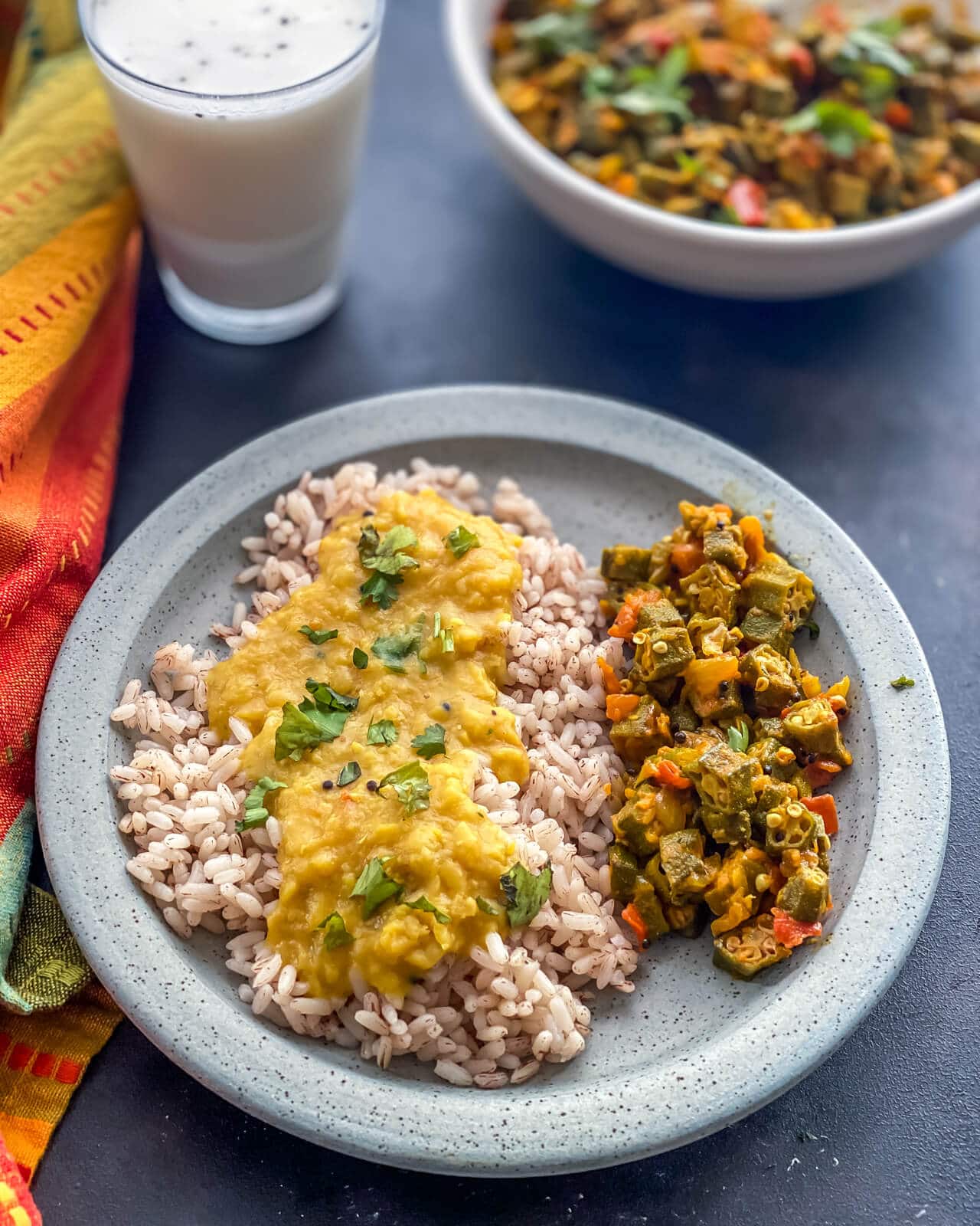 Bhindi subzi served with rice and dal in a grey plate
