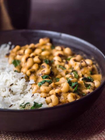 jeera rice served with black chowli in a black bowl