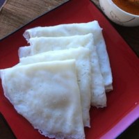 Neer dosa layered on red plate