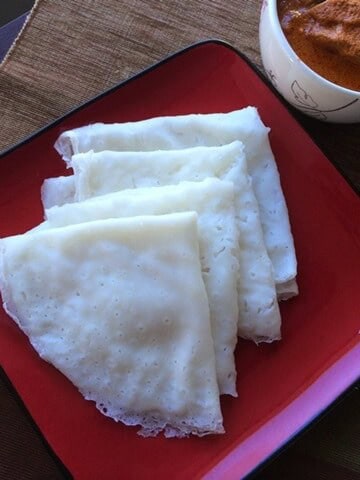 Neer dosa layered on red plate