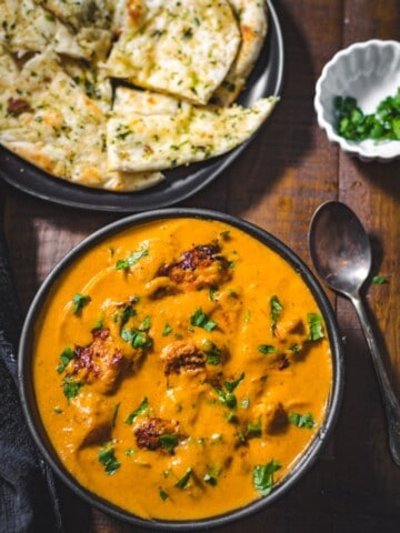 Chicken Tikka Masala served in a black bowl with garlic naan