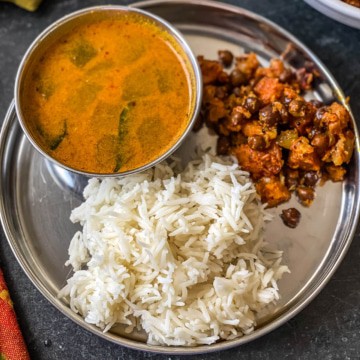 Rice served with kadle suran and rasam in a steel plate