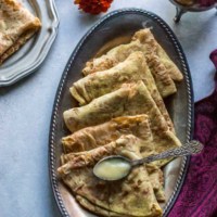 Puran poli folded in triangles is placed overlapping on a metal plate.