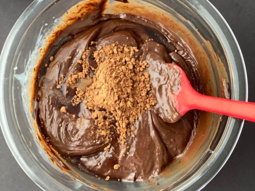 Vanilla essence and cocoa powder added to chocolate mixture in a glass bowl