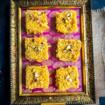 6 pieces of mango kalakand placed on a pink and golden tray