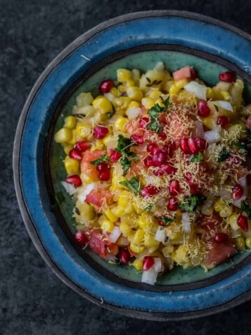 Corn chaat served in a blue bowl with sev