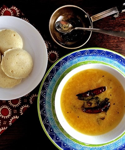 Dal tove served in a colorful bowl alongside idli