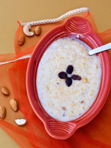 Cracked wheat payasam served with a red bowl with a spoon in it