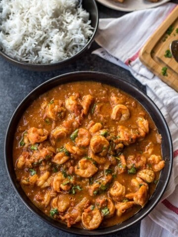 Prawns balchao served in a black bowl with a side of rice