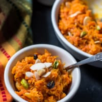 An overhead shot of carrot halwa served in white bowls.