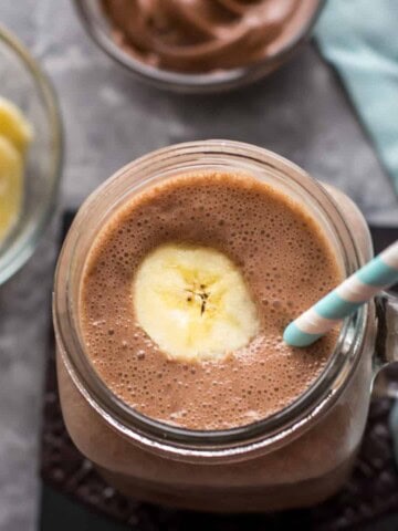 Overhead shot of banana nutella smoothie in a mason jar with a striped blue and white straw