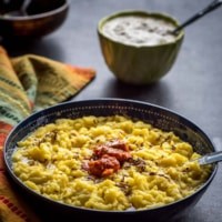 Khichdi served in a black bowl with pickle on top