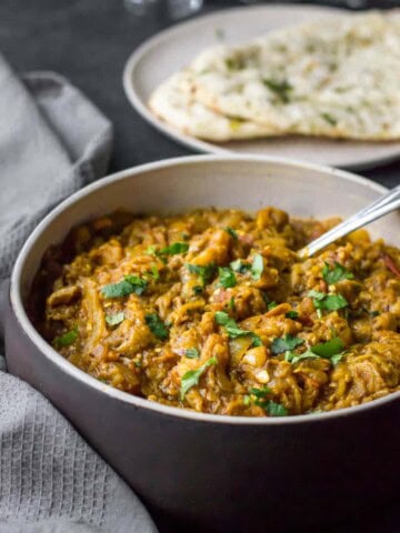 Bhaingan bharta served in a brown and white bowl served with naan
