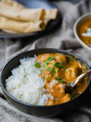 Chicken makhani served in a black bowl with rice and served with roti
