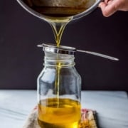 Ghee being placed into a sieve placed on a glass bottle
