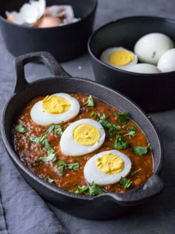 Egg curry served in a cast-iron pan with halved eggs as topping