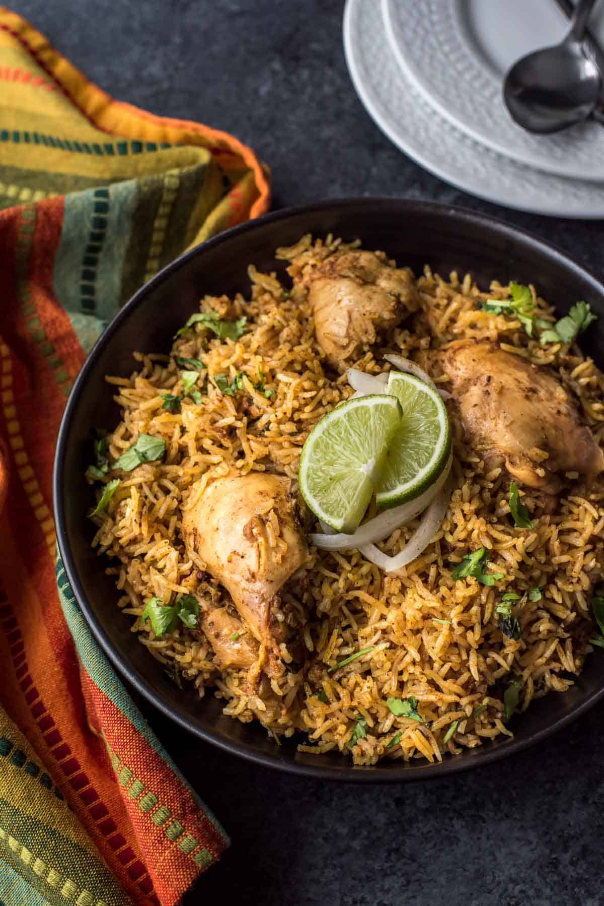 Chettinad Chicken biryani served with onions and lime in a black bowl