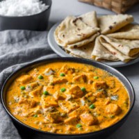 Matar paneer served in a black bowl alongside rotis
