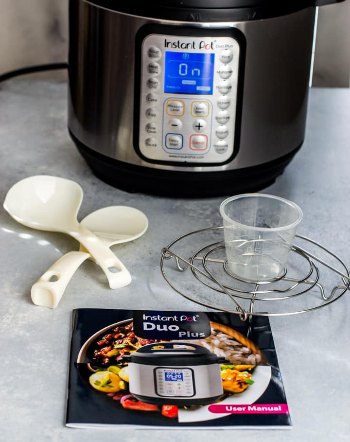 Instant Pot Duo Plus - What's inside the box - steam rack with handles, recipe booklet, serving spoon, soup spoon, and a measuring cup