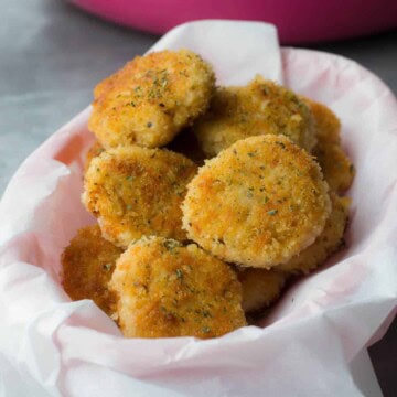 Chicken nuggets served in a bowl lined with parchment paper. Accompanied by glass of water and a pan in which chicken nuggets were made
