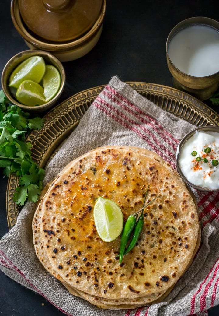Paneer paratha served with a side of lime, green chillies and yogurt