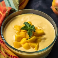 Mango raita served in a glass bowl and garnished with mint leaves