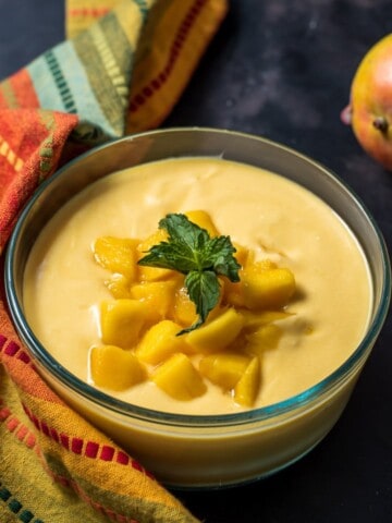 Mango raita served in a glass bowl and garnished with mint leaves