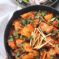 An overhead shot of chicken karahi garnished with ginger julienne