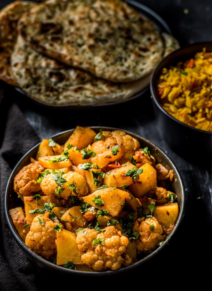 Aloo gobhi in a black bowl served with naan