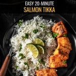 Full plate of the salmon tikka recipe with the salmon on a black plate with rice and garnished with lime wedges and cilantro. The food it on a black plate with a wooden handled fork on the left. The words easy 20 minute salmon tikka are typed at the top.