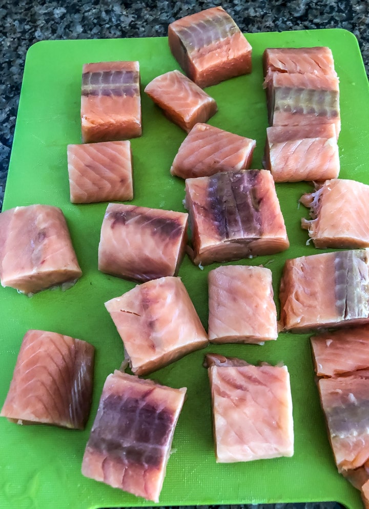 Wild caught salmon cut into cubes on a green cutting board for the salmon tikka recipe.