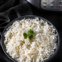 Basmati rice served in a black bowl placed in front of Instant Pot