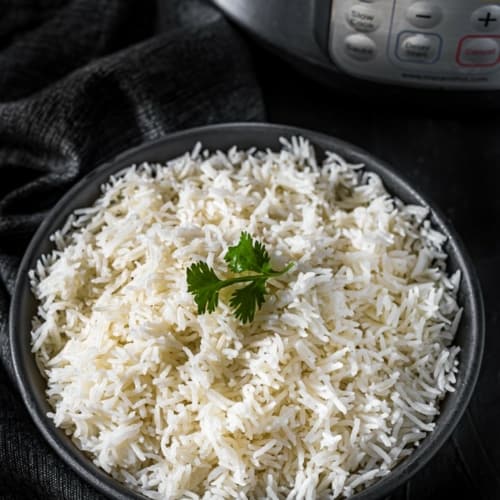 Basmati rice served in a black bowl placed in front of Instant Pot