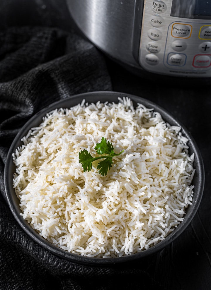 Basmati rice served in a black bowl placed in front of Instant Pot