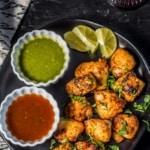 Chicken tikka served with green chutney and tamarind chutney along with lemon wedges
