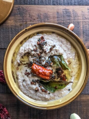 An overhead shot of peanut chutney in a brown ceramic bowl