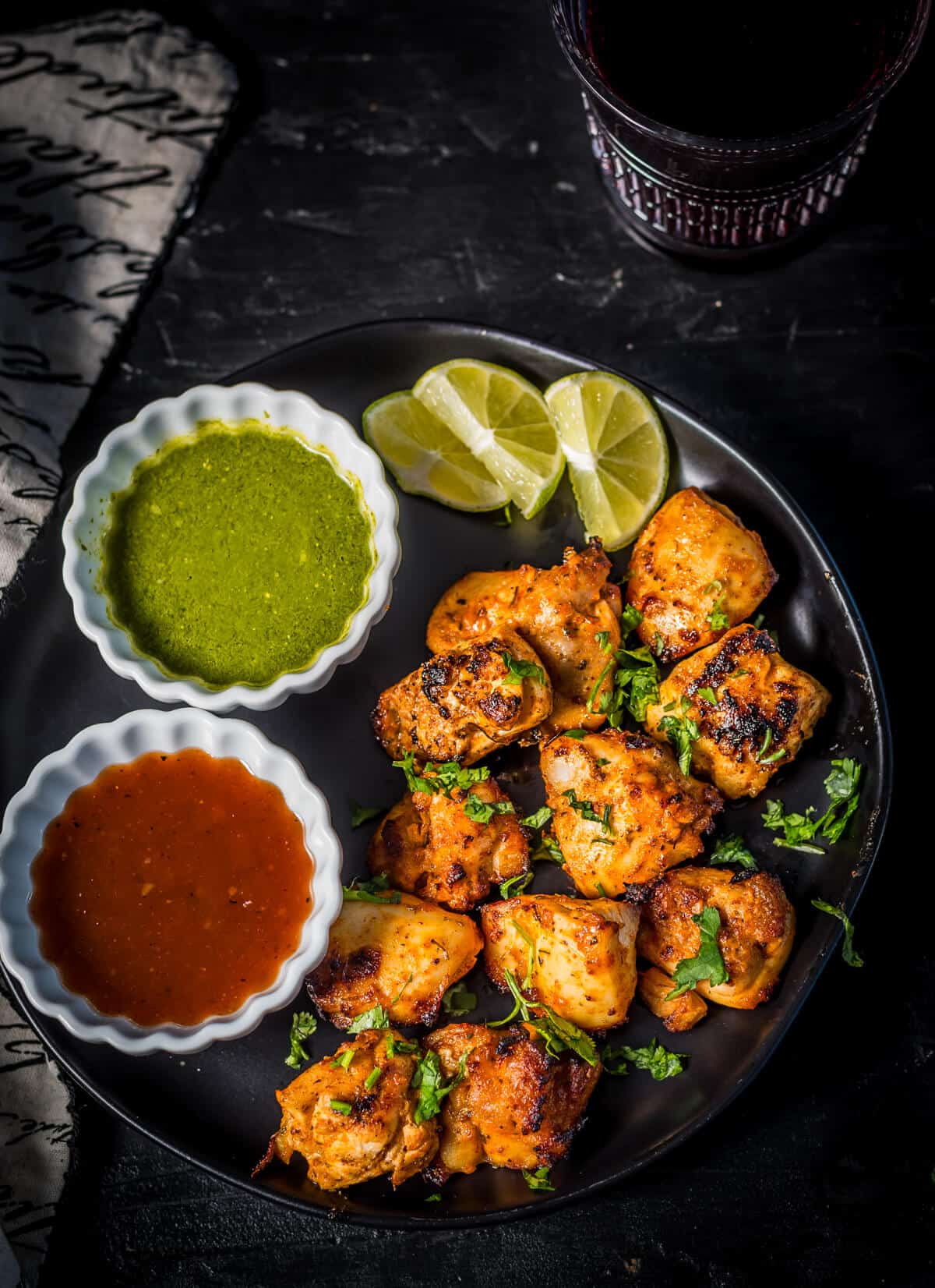 Chicken tikka served with green chutney and tamarind chutney along with lemon wedges