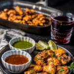 Chicken tikka served with green chutney and tamarind chutney along with lemon wedges with a glass of grape juice on the side
