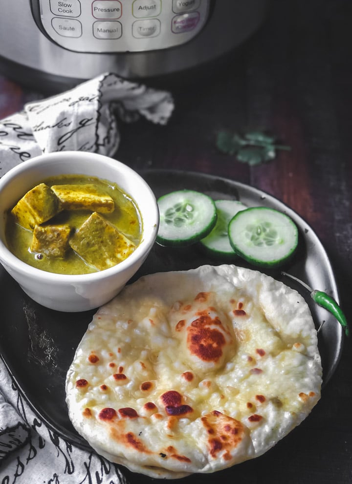 Plain butter naan served with palak paneer and cucumber slices