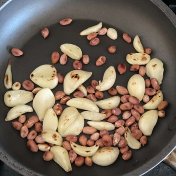 Garlic cloves and peanuts being roasted in a pan