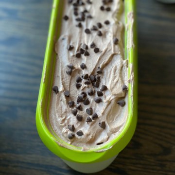 A green ice cream tub with double chocolate ice cream and chocolate chips on top.