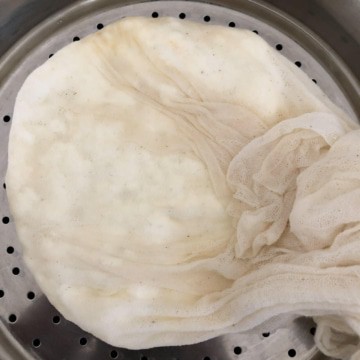 A cheesecloth on a colander gently squeezed to let go for excess whey.