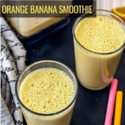 Two glasses of orange julius on a counter with two straws to the right, a cutting board of orange slices in the back, and a blender with orange smoothie in the back left with the words orange banana smoothie in yellow on the left.