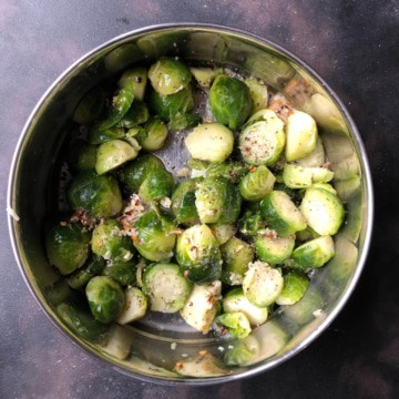 Brussel sprouts with seasoning in a silver bowl.