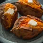 The words Instant Pot in white and Sweet potato in yellow with a blue plate with three sweet potatoes topped with butter.