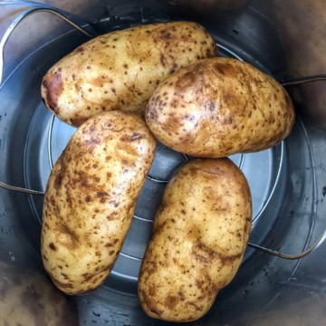 Four potatoes on a trivet inside the instant pot before cooking.