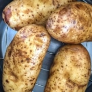 The words Instant Pot in white and steamed potatoes in yellow at the top with a picture of four steamed potatoes in the instant pot.
