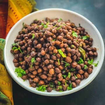 Black chickpeas (kala chana) served in a white bowl with a multi color napkin on the side